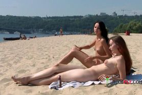 Nudist teen with brown hair is sitting down on the beac