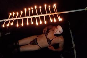 Candles are hanging on her body with an anal plug in